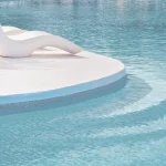 bazen sa bijelim kamenom, ležaljkama i svijetlo plavom boje vode