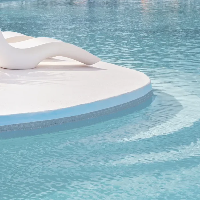 bazen sa bijelim kamenom, ležaljkama i svijetlo plavom boje vode