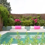 Bazen sa zelenim mozaik pločicama i plažom sa namještajem i biljkama