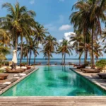 bazen sa svijetlo zelenom bojom vode i mozaik pločicama okružen palmama