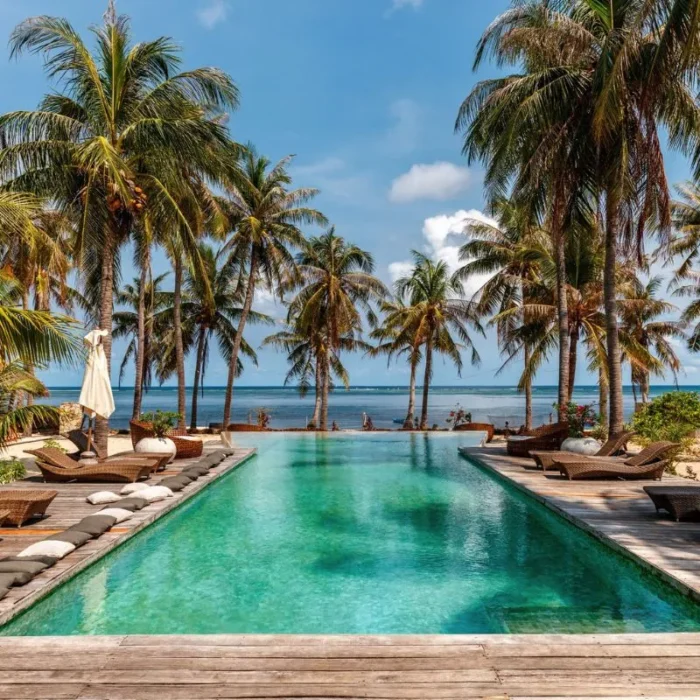 bazen sa svijetlo zelenom bojom vode i mozaik pločicama okružen palmama